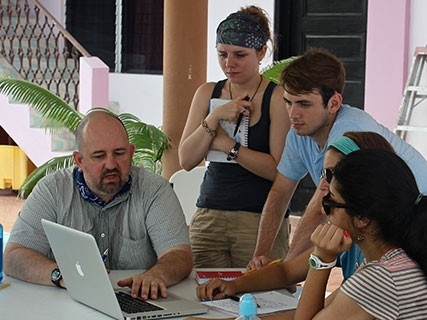 People gather around a computer receiving guidance on data collection