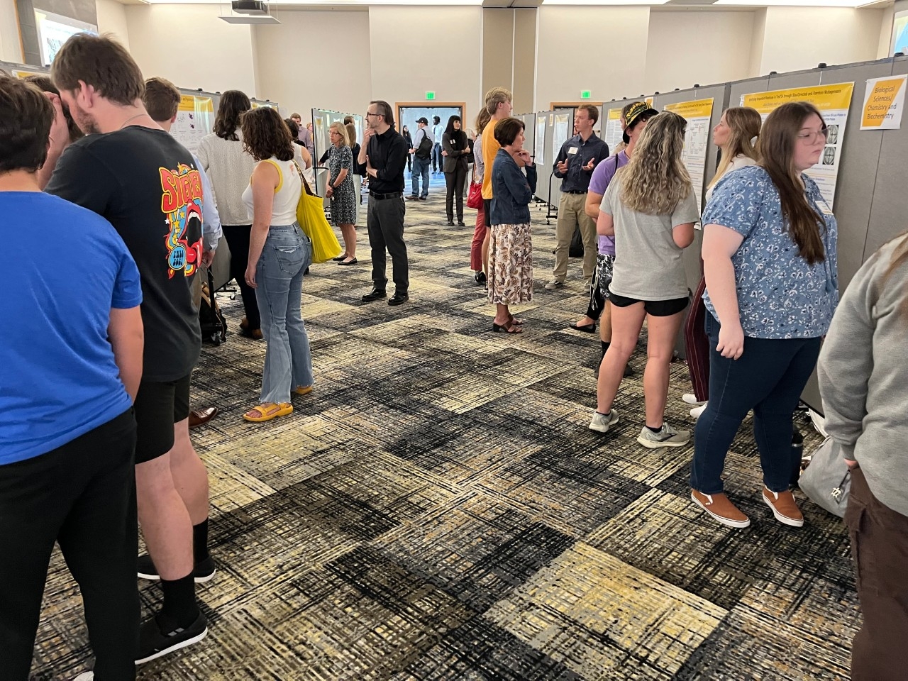 Multiple students presenting research posters to visitors