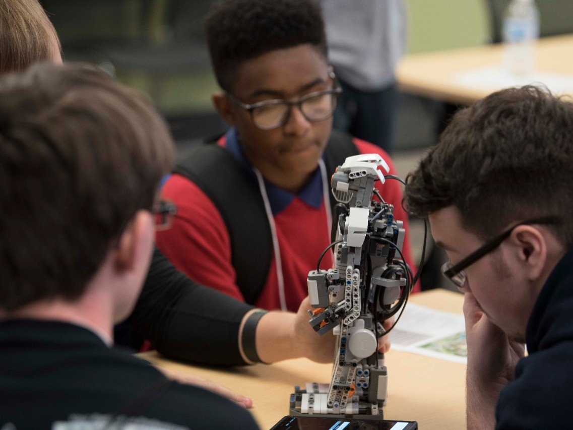 High school students programming a robot at High School STEM+H Day event