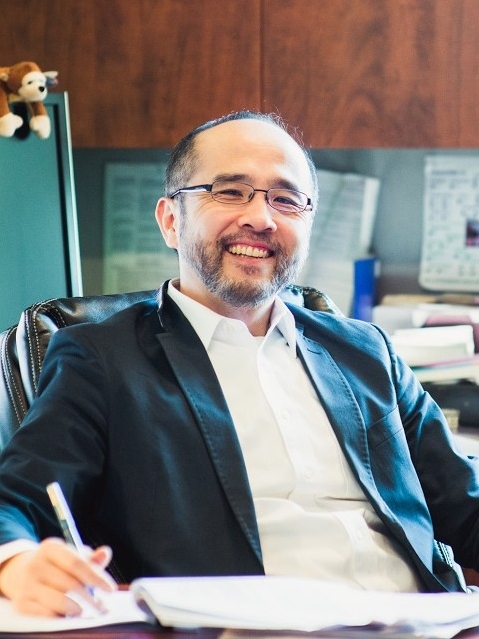 Dr. Francis Su smiles at his office desk.