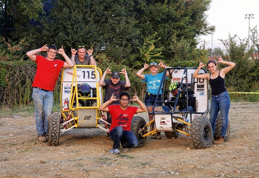 Members of Norse Baja give the "Norse Up" hand signal outside next to their custom-made dune buggies.
