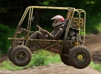 The SAE Baja vehicle in the middle of a jump, driven by a student