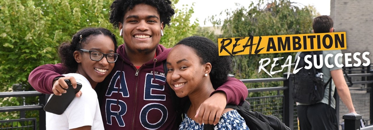 Three students holding each other in an embrace 