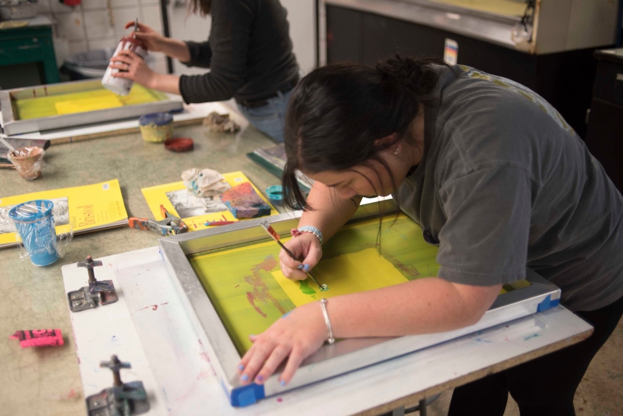 Student working on a painting in classroom.