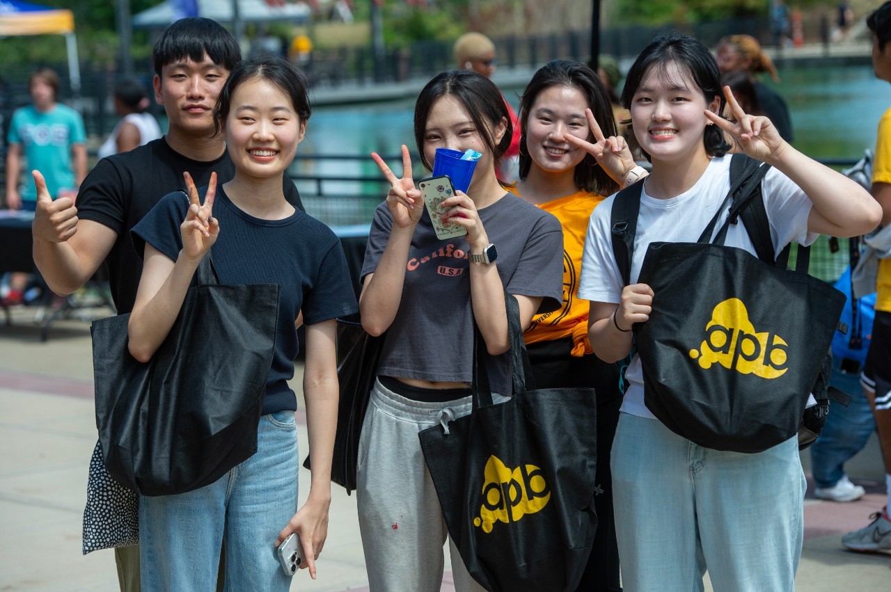 Group of students by Loch Norse giving peace signs.